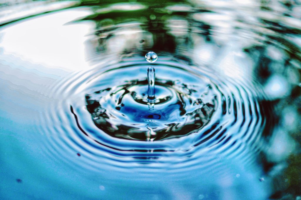Decorative image. Water droplet in a pool or pond of water.